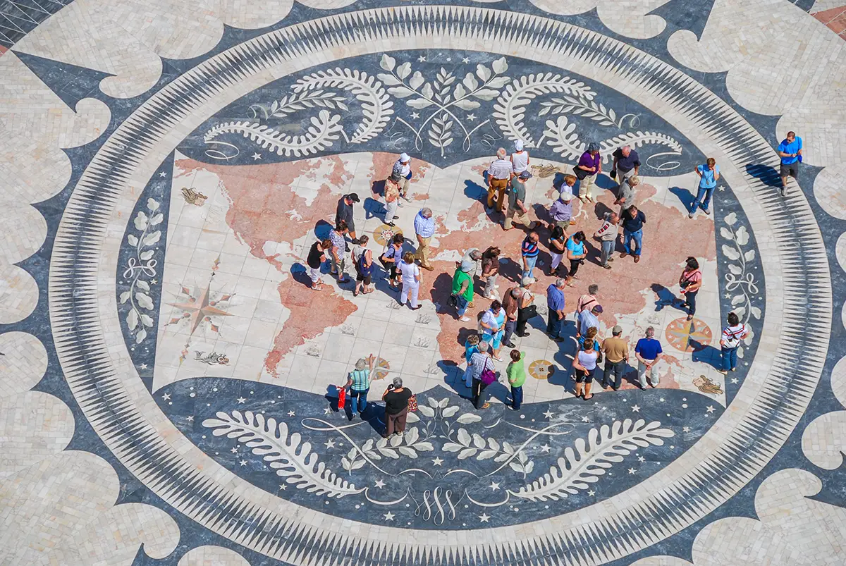 Group of tourists looking at the mosaic of the ancient world map in Lisbon.