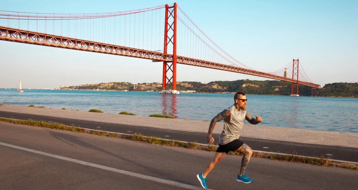 Expat running alongside the Tagus River, with an amazing view of the 25th of April bridge in Lisbon.