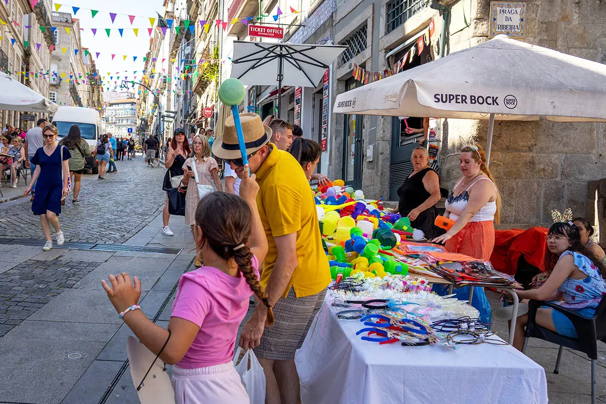 Picture of a girl gently tapping a man on the head with a plastic, toy hammer; one of Porto's São João's traditions.