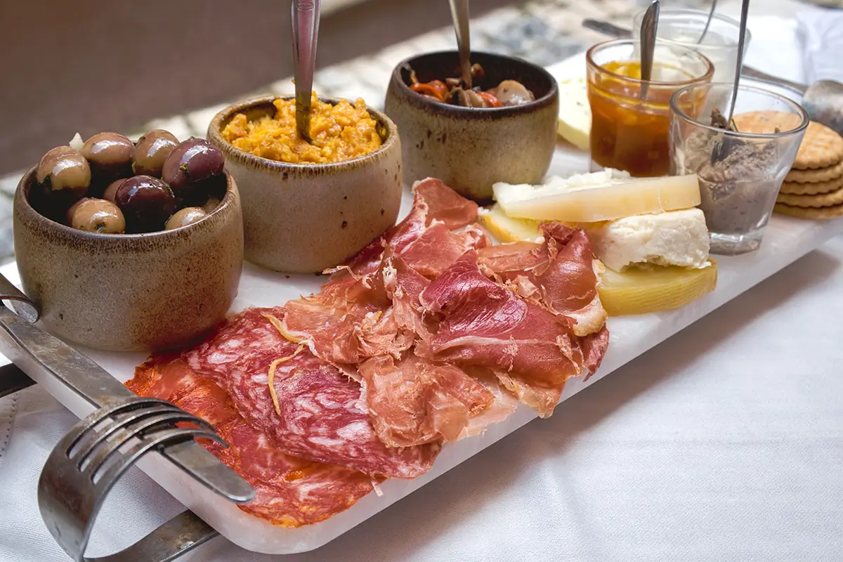 A table with a mix of typical Portuguese tapas; cheeses, olive oils and deli meats.